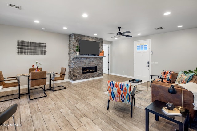 living room with ceiling fan, a fireplace, and light hardwood / wood-style floors