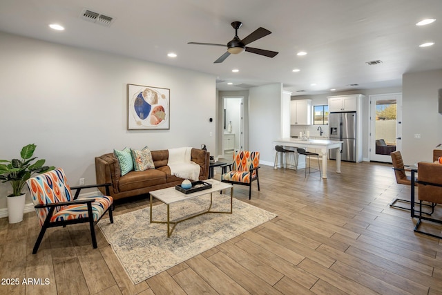 living room featuring ceiling fan and light hardwood / wood-style flooring