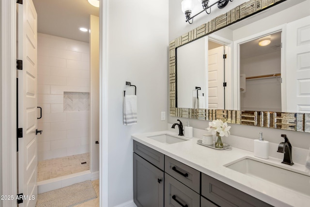 bathroom with tile patterned flooring, vanity, and tiled shower