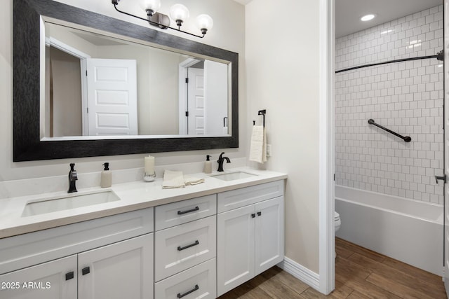 full bathroom featuring tiled shower / bath, vanity, and toilet