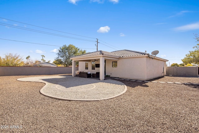 rear view of property with ceiling fan and a patio area