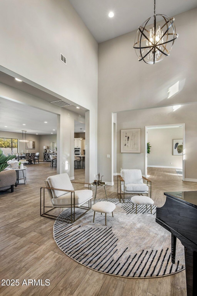 living room featuring light hardwood / wood-style floors, a high ceiling, and a notable chandelier