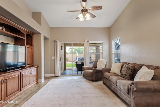 living room featuring light wood-style floors, baseboards, and a ceiling fan