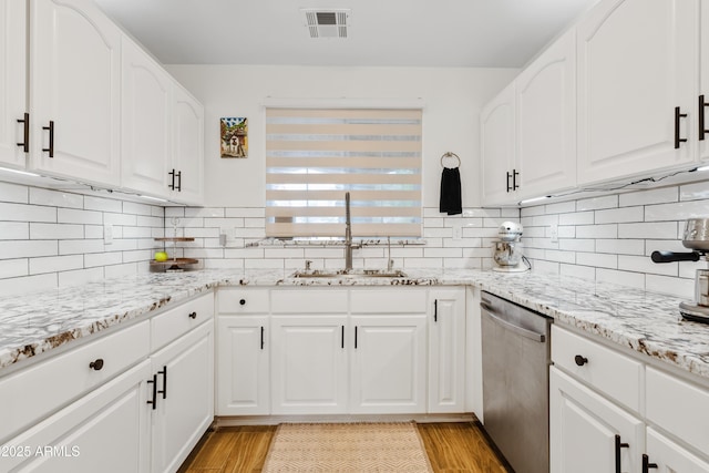 kitchen featuring stainless steel dishwasher, a sink, light wood-style flooring, and visible vents
