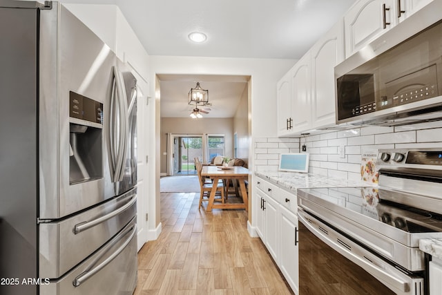 kitchen with white cabinets, stainless steel appliances, light wood-style flooring, and tasteful backsplash