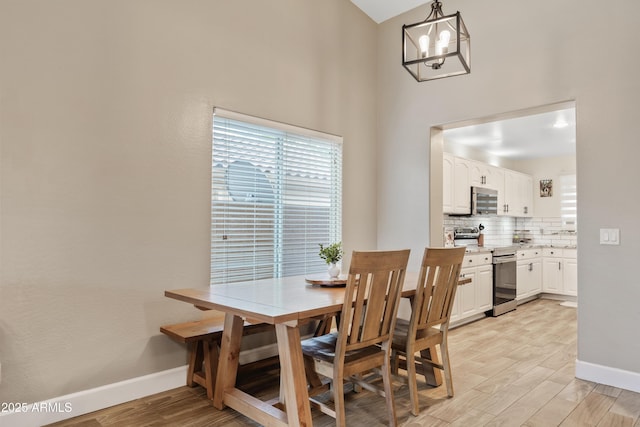 dining area with baseboards, light wood-style floors, and an inviting chandelier