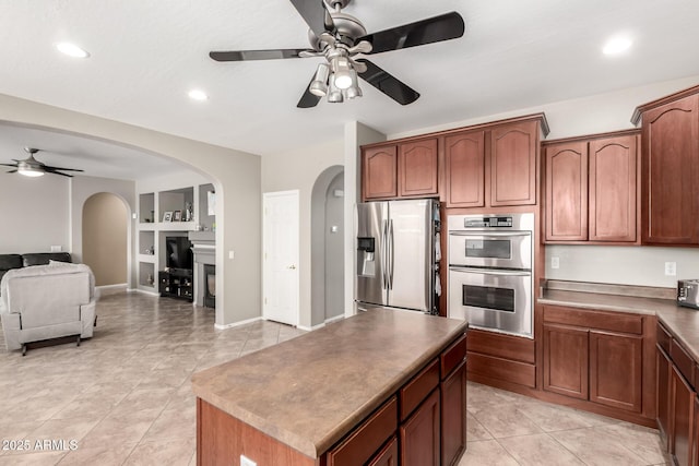17005 S Coleman St, Phoenix, AZ 85045 - kitchen featuring a kitchen island, built in shelves, appliances with stainless steel finishes, arched walkways, and ceiling fan