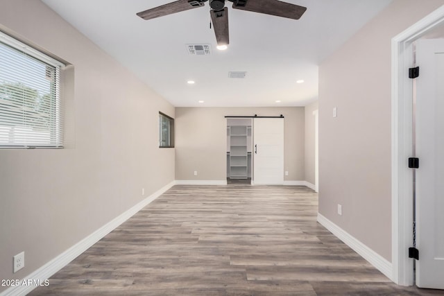 interior space with a barn door, wood finished floors, visible vents, and baseboards