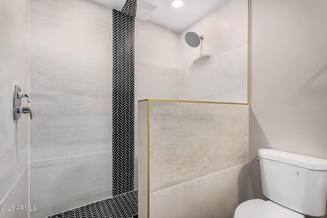 bathroom featuring toilet and a tile shower