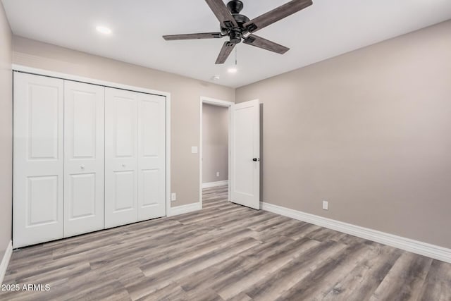 unfurnished bedroom with ceiling fan, a closet, baseboards, and wood finished floors