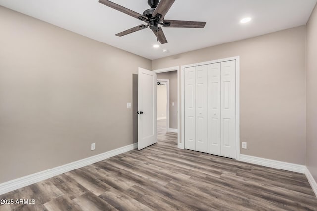 unfurnished bedroom featuring a ceiling fan, wood finished floors, baseboards, and a closet