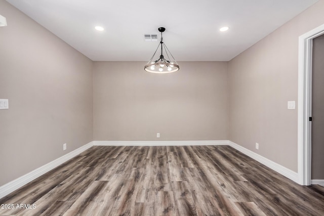 empty room featuring visible vents, baseboards, and dark wood-type flooring