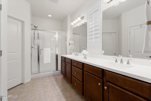 bathroom with walk in shower, tile floors, vanity with extensive cabinet space, and dual sinks