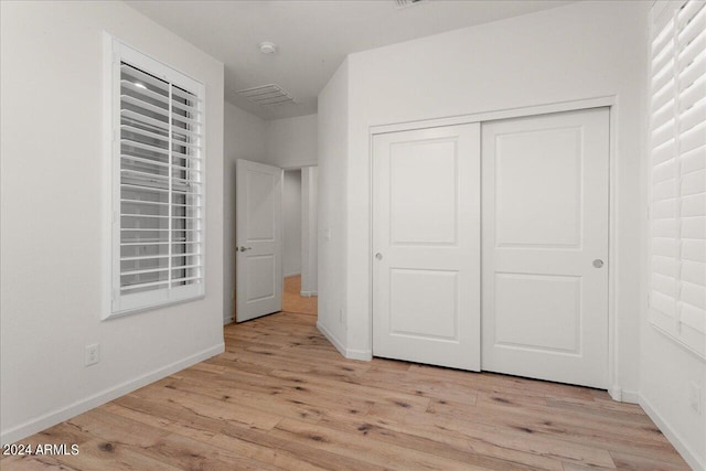 unfurnished bedroom with light hardwood / wood-style flooring and a closet