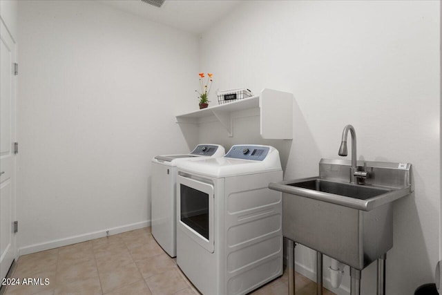 clothes washing area featuring sink, light tile floors, and washer and clothes dryer