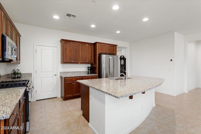 kitchen featuring appliances with stainless steel finishes, a kitchen island with sink, light tile floors, and sink