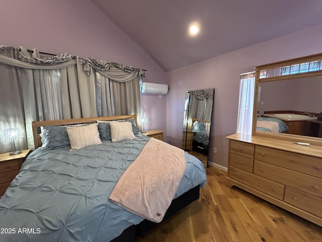 bedroom with lofted ceiling, wood finished floors, baseboards, and a wall mounted AC