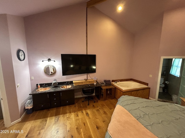 bedroom with light wood-style floors, built in study area, vaulted ceiling with beams, and baseboards