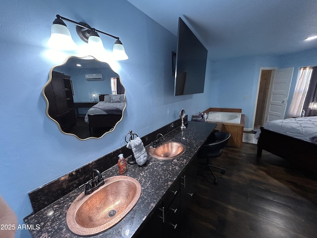 bathroom with double vanity, a garden tub, a sink, and wood finished floors