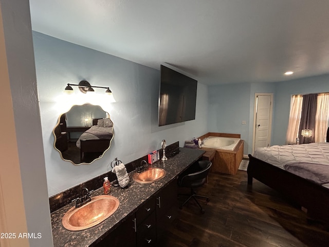 bathroom with double vanity, wood finished floors, a sink, and a bath