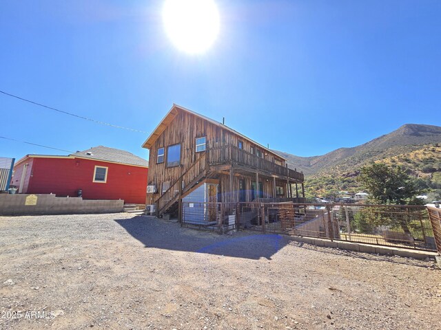 rear view of property with stairs and a mountain view