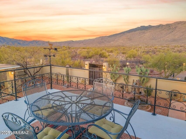 balcony at dusk featuring outdoor dining space and a mountain view