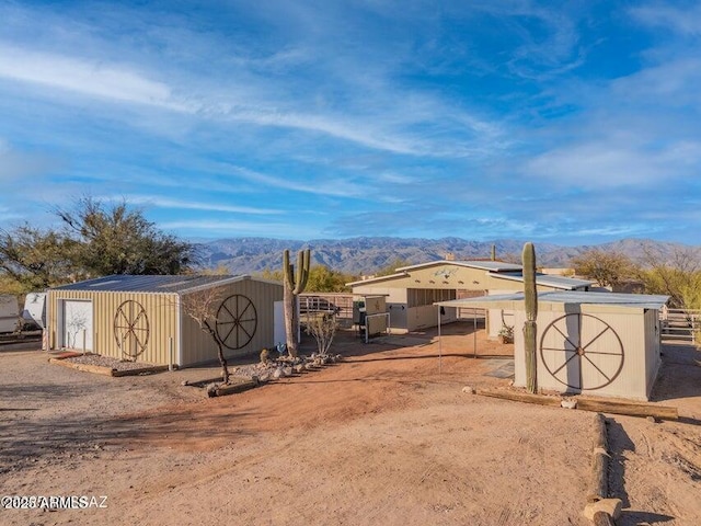 view of yard featuring an outdoor structure, a mountain view, fence, and a shed