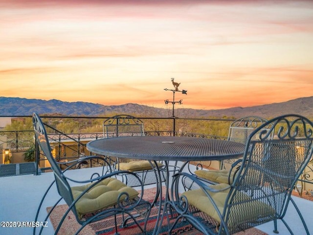 balcony at dusk featuring a mountain view and outdoor dining space
