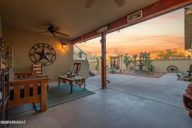 patio terrace at dusk featuring fence and ceiling fan