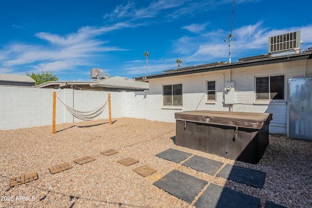 rear view of property with central air condition unit, a patio area, a hot tub, and a fenced backyard