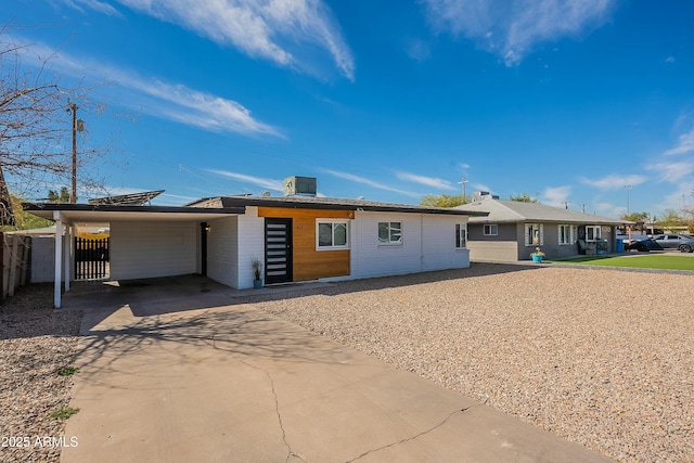 single story home with concrete driveway, an attached carport, central AC unit, and fence