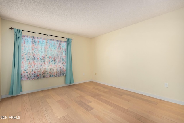 unfurnished room featuring a textured ceiling and light hardwood / wood-style flooring