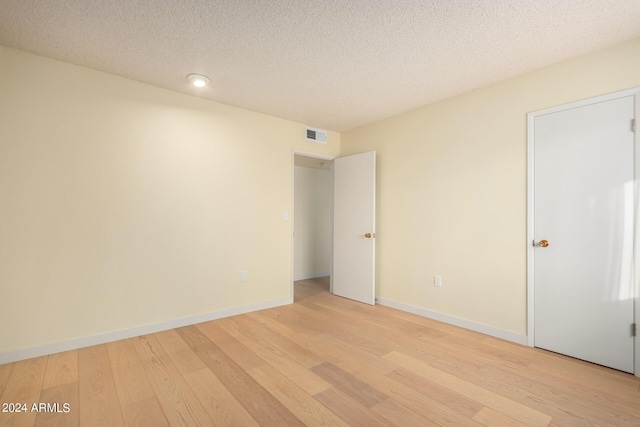 spare room featuring a textured ceiling and light hardwood / wood-style flooring