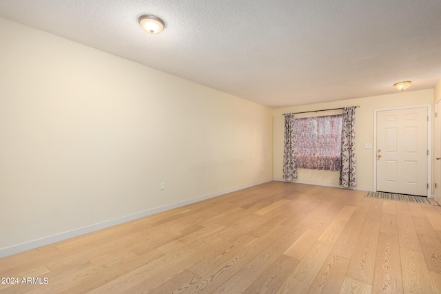 spare room with light hardwood / wood-style floors and a textured ceiling