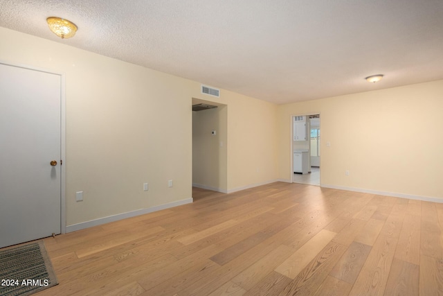 empty room featuring light wood-type flooring and a textured ceiling