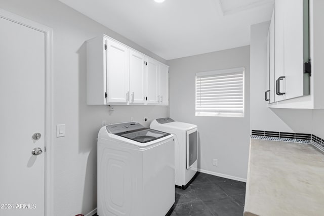 clothes washing area featuring washer and dryer, cabinets, and dark tile patterned floors