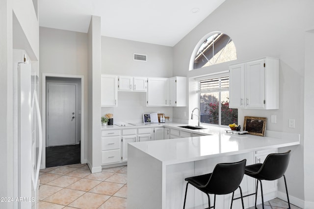 kitchen with white cabinetry, sink, white refrigerator with ice dispenser, kitchen peninsula, and light tile patterned floors