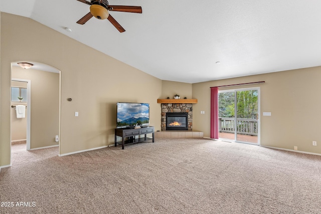 69 E Mohawk Dr, Flagstaff, AZ 86005 - carpeted living area featuring a stone fireplace, a ceiling fan, vaulted ceiling, baseboards, and arched walkways