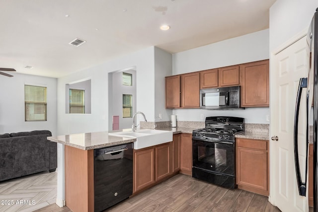 20261 W Desert Bloom St, Buckeye, AZ 85326 - kitchen with visible vents, a sink, black appliances, a peninsula, and open floor plan