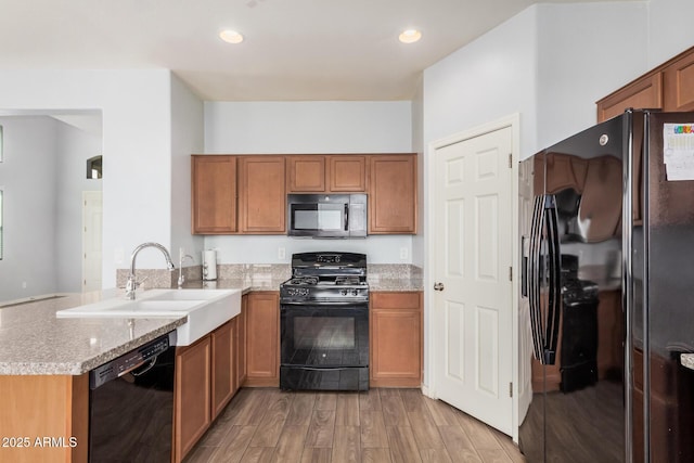 20261 W Desert Bloom St, Buckeye, AZ 85326 - kitchen with a sink, light wood-style floors, brown cabinetry, a peninsula, and black appliances