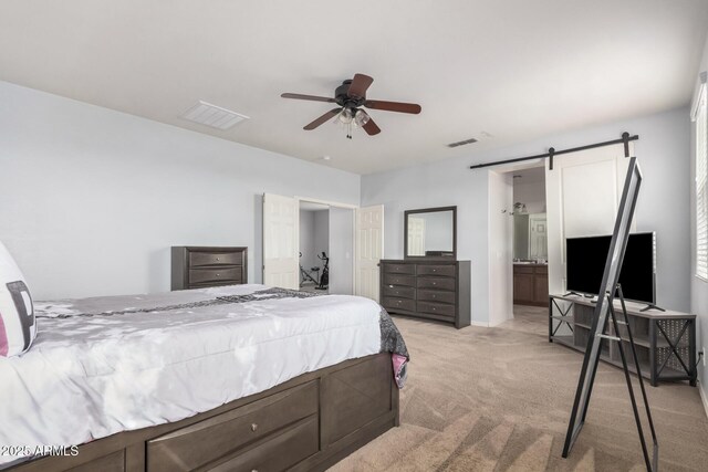20261 W Desert Bloom St, Buckeye, AZ 85326 - bedroom featuring visible vents, a barn door, ceiling fan, and light colored carpet
