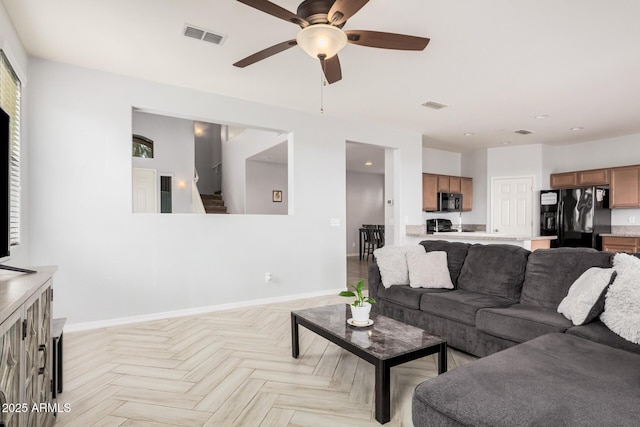 20261 W Desert Bloom St, Buckeye, AZ 85326 - living area featuring a ceiling fan, baseboards, visible vents, and stairway