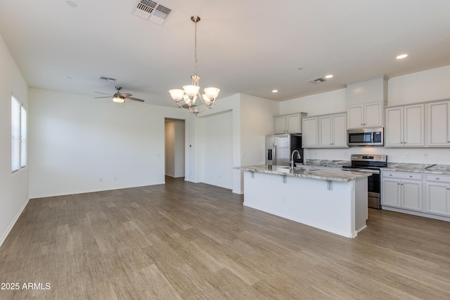 14870 W Encanto Blvd Unit 2006, Goodyear, AZ 85395 - kitchen with stainless steel appliances, wood finished floors, a chandelier, open floor plan, and recessed lighting