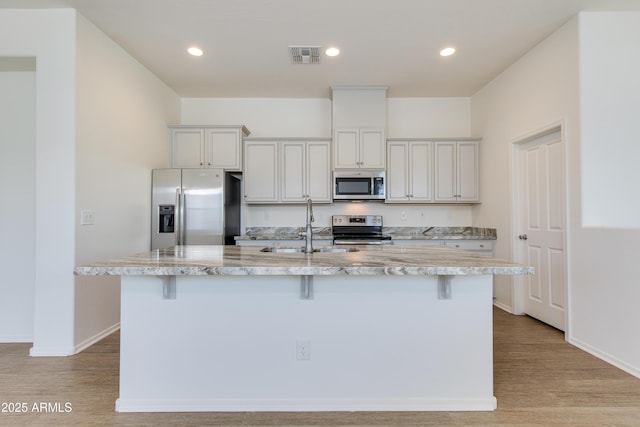 14870 W Encanto Blvd Unit 2006, Goodyear, AZ 85395 - kitchen featuring stainless steel appliances, a breakfast bar area, an island with sink, light wood finished floors, and recessed lighting