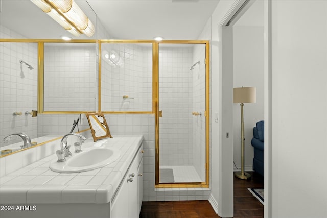 bathroom with hardwood / wood-style floors, vanity, and an enclosed shower