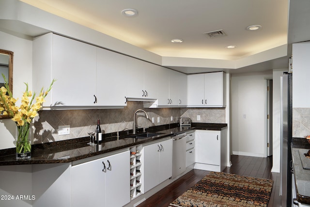 kitchen featuring stainless steel appliances, dark wood-type flooring, sink, dark stone countertops, and white cabinets