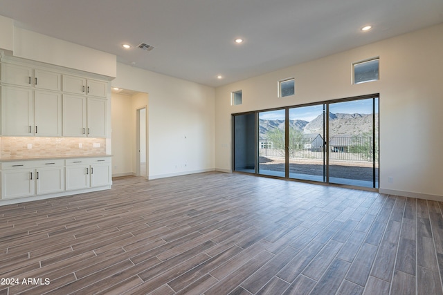 unfurnished living room featuring visible vents, recessed lighting, baseboards, and wood finish floors