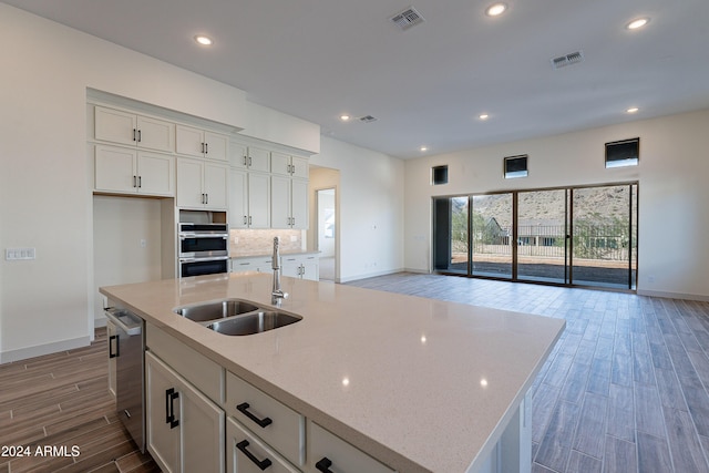 kitchen with visible vents, white cabinetry, open floor plan, and a sink