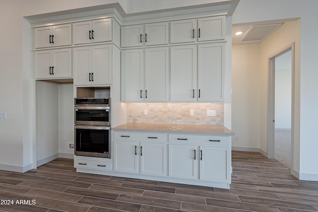 kitchen featuring stainless steel double oven, visible vents, backsplash, and wood tiled floor