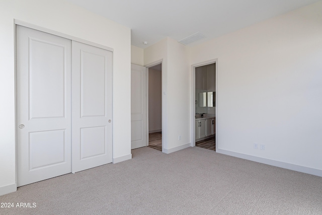 unfurnished bedroom featuring baseboards, a closet, carpet floors, and connected bathroom